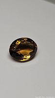 Oval cut Madeira Citrine gemstone showing deep cognac color and polished facets, photographed on a neutral background