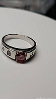 Men's ring with red moissanite center stone and clear accent stones on silver band