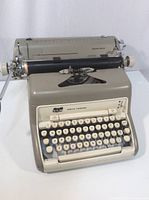 Front view of beige Smith Corona SCM manual typewriter, showing round white keys and brand label.