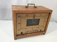 Front view of the vintage Bendix Aviation Corporation tube style radio in wooden case with visible clock face and tuning scale