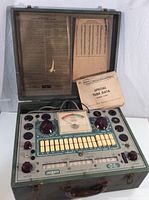 Open tester in metal carrying case showing front panel, hinged lid instructions and tube data booklet resting on panel.