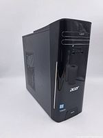 Front and side angle showing glossy black Acer Aspire desktop computer tower with multiple front I/O ports and Intel Core i series sticker.