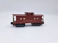 Side view of red American Flyer Lines HO scale caboose marked 930, showing windows, railings, and wheels.