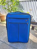 Front view of blue suitcase showing two zippered front pockets and top handle
