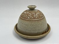 Full view of the vintage ceramic lidded dish showing the dome lid with decorative carved scroll pattern and knob handle on top, resting on the round base.