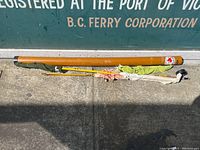 Full view of the brown cylindrical fishing rod travel case, one yellow fishing rod and a green fabric wrap.