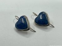 Pair of heart-shaped earrings with blue lapis lazuli stones set in sterling silver with hook backs, front view.