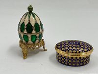 Photo of egg-shaped and oval trinket boxes side by side on white background