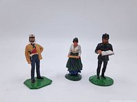 Three hand-painted toy soldiers, front view showing all three figures on green bases with detailed uniforms and accessories