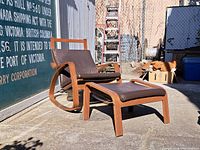 Reclining chair with footrest outdoors on concrete with chain-link fence and industrial backdrop