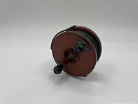 Front angled view of the vintage wooden fishing reel with two crank knobs and visible fishing line.