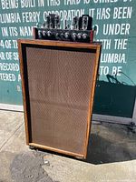 Front view of wooden speaker console with amplifier unit on top