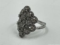 Front angle view showing cluster of small stones set in scalloped design on sterling silver ring.