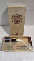 Original box with emblem and three spools of silk thread (two black, one white) inside, showing the label and contents.