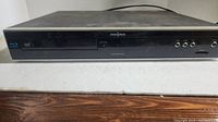 Front view of black Insignia Blu-ray player showing disc tray, buttons, and logos.