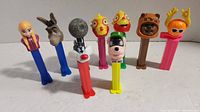 Photo showing nine colorful Pez dispensers with various character heads including Elsa, Donkey, the Death Star, Muppet characters, Goofy, Wicket Ewok, and Flame.