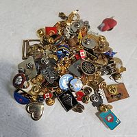 Various pins piled together showing a mix of shapes, logos, and enamel colors.