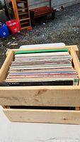 View of wooden crate filled with vinyl records, focused on the top edge of the records