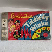Colorful box of Combination Tiddledy Winks game with illustrations of children and bowling pins, wrapped in plastic with wear shown.
