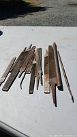 Overview of multiple metal files laid out on a table, showing assorted shapes and sizes with rust and wear.