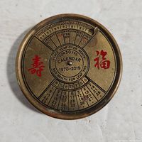 Top view of the vintage brass perpetual calendar showing the years 1970-2019, months, days of the week, and Asian characters in red.