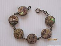 Full view of the round abalone shell discs connected by sterling silver links with the clasp visible.