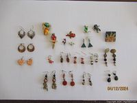 Overview photo showing all jewelry pieces spread on a white background, including earrings, brooches, and pins in various shapes and colors.