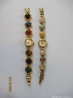 Two vintage Cardini ladies wristwatches with carved scarab beetle cabochon multi-color chain link bracelets side by side on white background.
