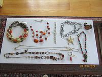 Full lot laid flat on white surface showing all necklaces, bracelet, watch, pin and key chain.
