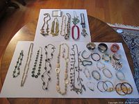 Top-down image of full assortment showing bracelets and necklaces on white surfaces across two tables