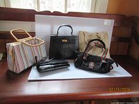 Group shot showing all five handbags together on a wooden surface near a window.