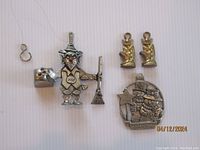 Full lot showing pewter lucky gnome bell ornament, two gold-tone pixy charms, and Christmas snowman ornament.