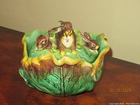 Front view showing majolica cabbage-shaped butter keeper with three rabbits on rim