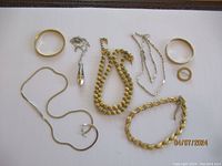 Multiple Monet jewelry pieces including necklaces, bracelets, and rings arranged on a white surface, showing various shapes and metal finishes.