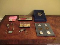 Full lot with six lapel pins, Sheaffer pen set, keychains, Buttons of Love, and Zina digital photo viewer keychain on table