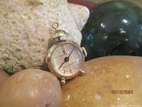 Front view of the Sovereign gold tone pendant watch showing dial and winding crown.