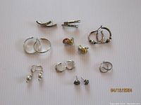 Overview photo showing the group of 11 assorted sterling silver earrings including hoops, studs, and clip-ons in varied condition.