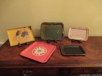 Five vintage toleware trays displayed together on wooden surface.