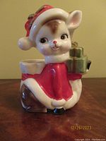 Front view of vintage Relpo Santa's reindeer ceramic planter wearing a red cape and hat, carrying green gift boxes