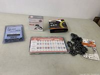 Lot of automotive and tool items including a car fuse kit, chainsaw chains, and two small boxed items including a USB audio coupler and a sanding pad.