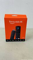 Front view of the sealed box showing the Fire TV Stick 4K device and remote with streaming service logos.