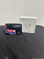 LUDOS wired headphones in black metal tin and sealed white Pro 4 wireless headphones box side view