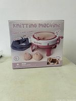 Box front showing the knitting machine and yarn balls, with branding and product details