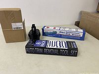 Photo of the boxed Auto Trim Removal Tool Set, boxed Multifunctional Sink Wrench, and Crearest battery in original packaging.