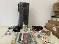 Complete overview of the lot items including the black kitty litter mat rolled vertically, spray bottle, multiple packs of collars, wrapped pet toys, leashes, and harnesses.