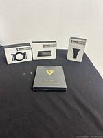 Four boxed Ridge accessories displayed next to a black GSoiax branded wallet box on a black surface against a white wall.