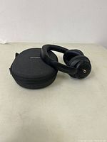 Black Soundcore over-ear headphones resting beside a black fabric zippered carrying case with white Soundcore logo.