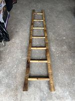 Top view of the bamboo ladder showing all six rungs and bamboo texture on a grey concrete floor.