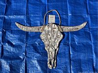 Front photo of wooden bull skull wall art showing curved horns, distressed white finish with rustic brown chipping effects.