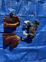 Photo of two brown ceramic horse head bookends and one grey ceramic horse statue with harness, placed on blue tarp.